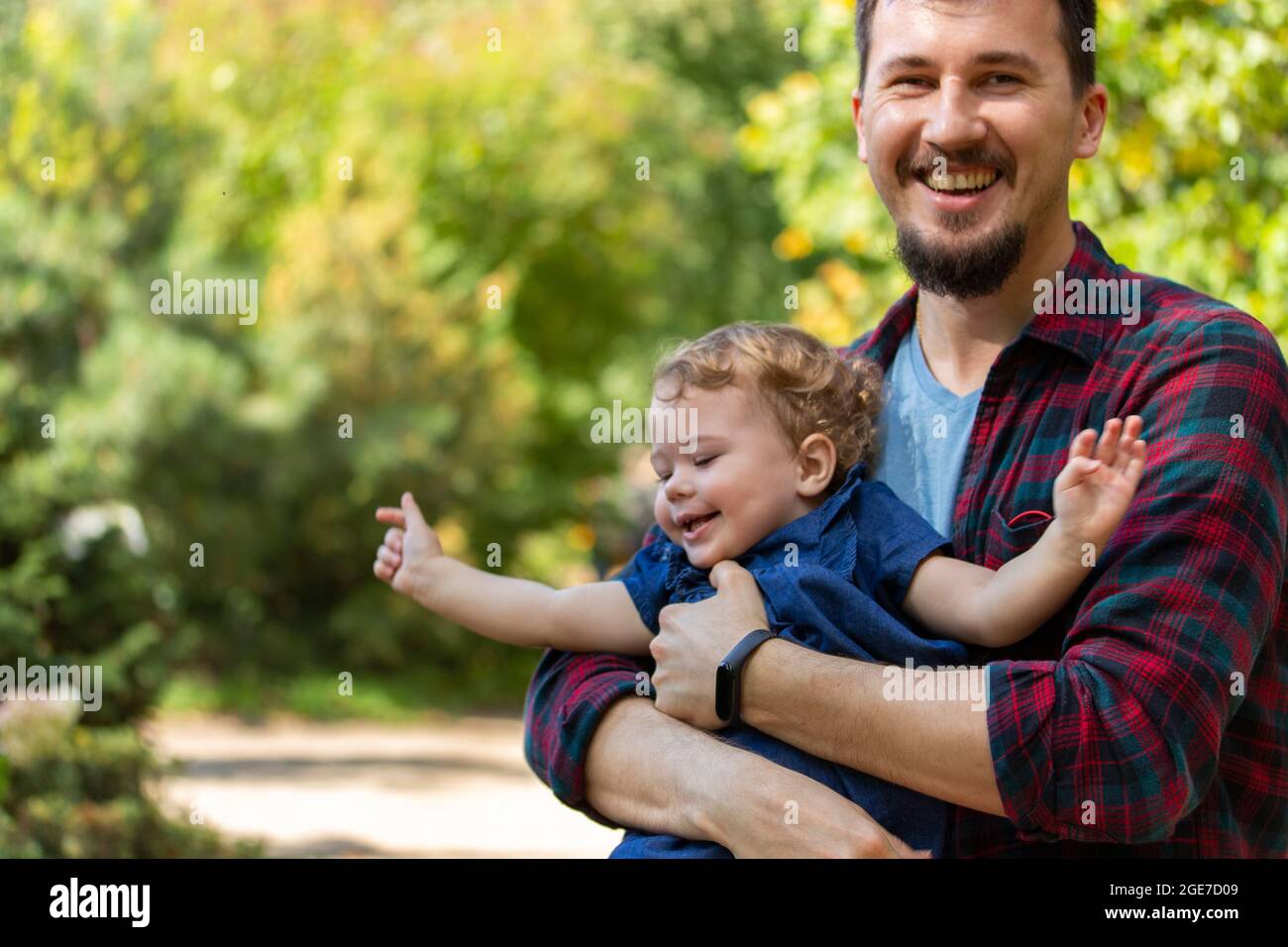 Giovane padre che tiene la bambina fra le braccia, famiglia felice. Papà e figlia ridendo volti felici Foto Stock