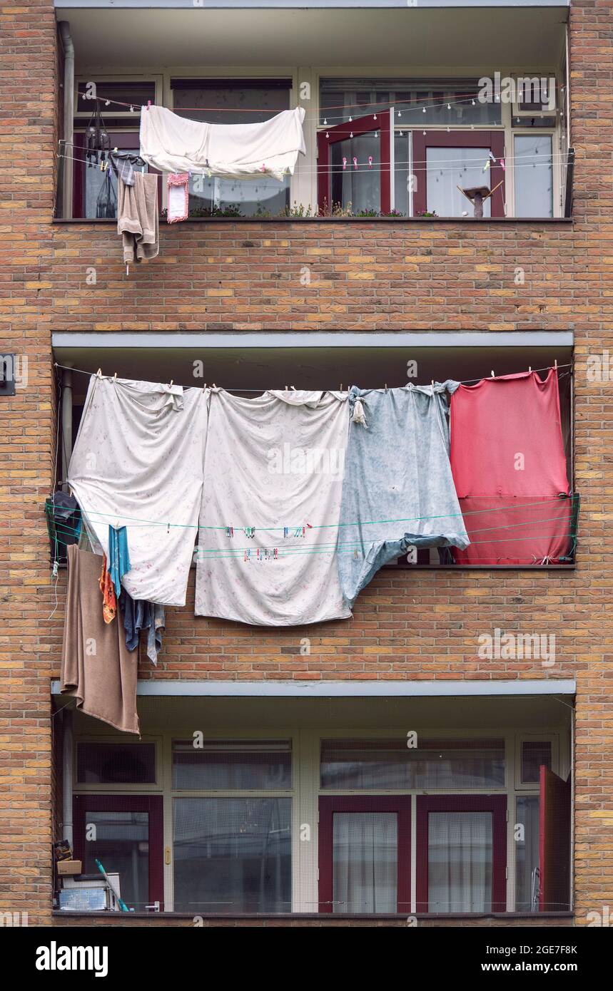I lavaggi sono appesi ad asciugare sulle linee di vestiti che si stagliano attraverso i balconi di un edificio di appartamenti nei Paesi Bassi Foto Stock