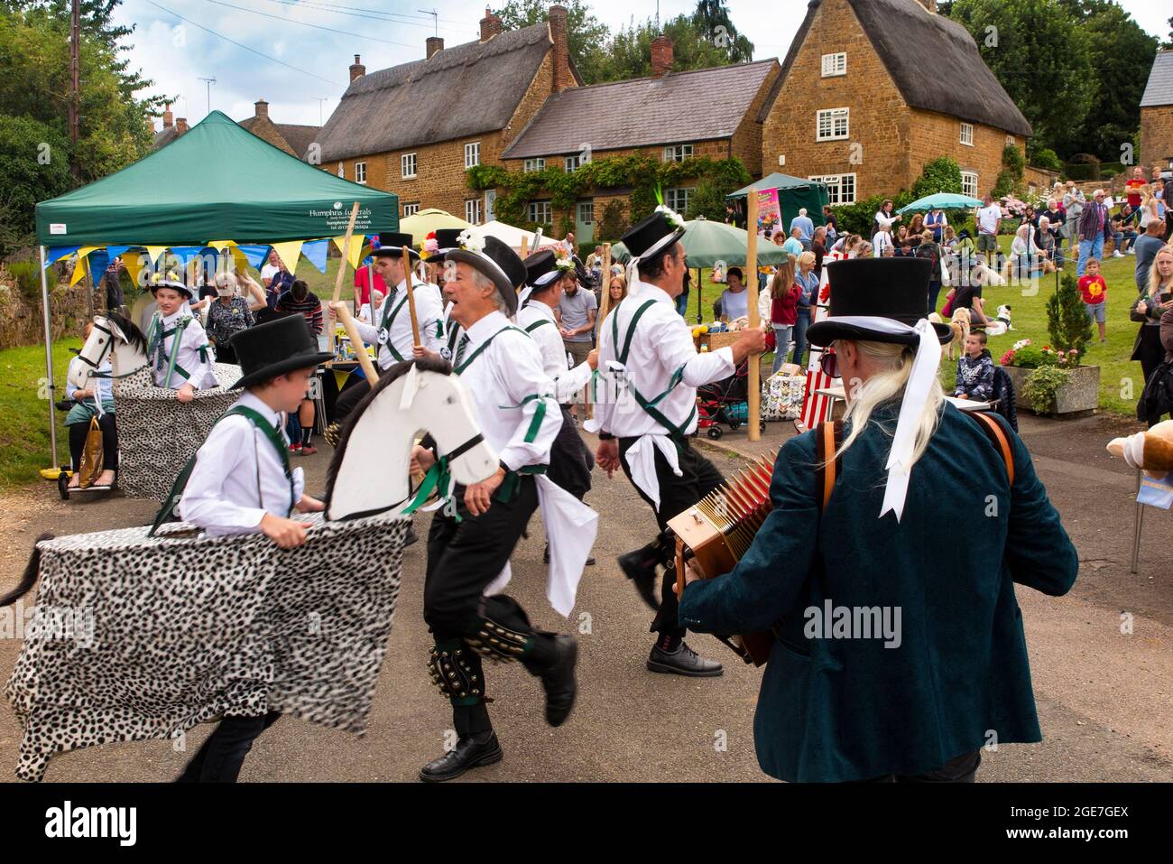 Regno Unito, Inghilterra, Oxfordshire, Wroxton, festa annuale della chiesa in corso, ballerini Morris con bastoni su Main Street, al bordo del villaggio verde Foto Stock