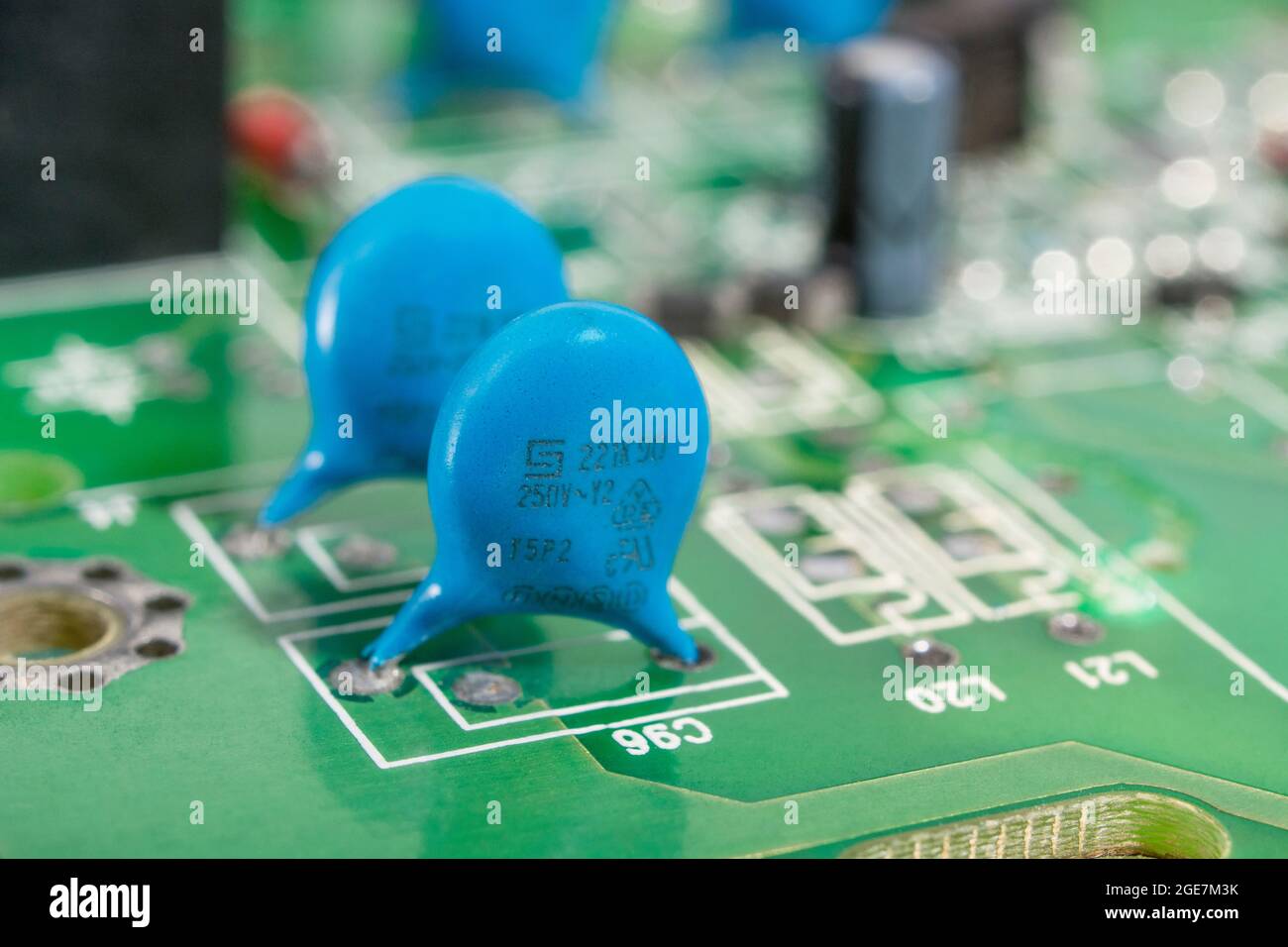 Immagine ravvicinata dei condensatori a disco in ceramica di colore blu su un circuito stampato verde. Per condensatore con terminali, piccoli componenti elettronici. Produttore di condensatori non noto. Foto Stock