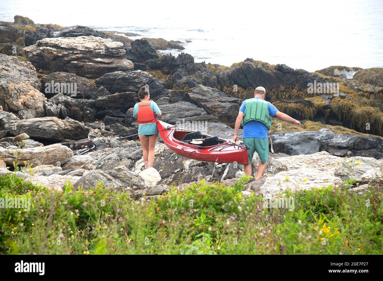 Una coppia si prepara a lanciare un kayak al largo della costa rocciosa di East Boothbay, (Ocean Point), Maine, USA Foto Stock