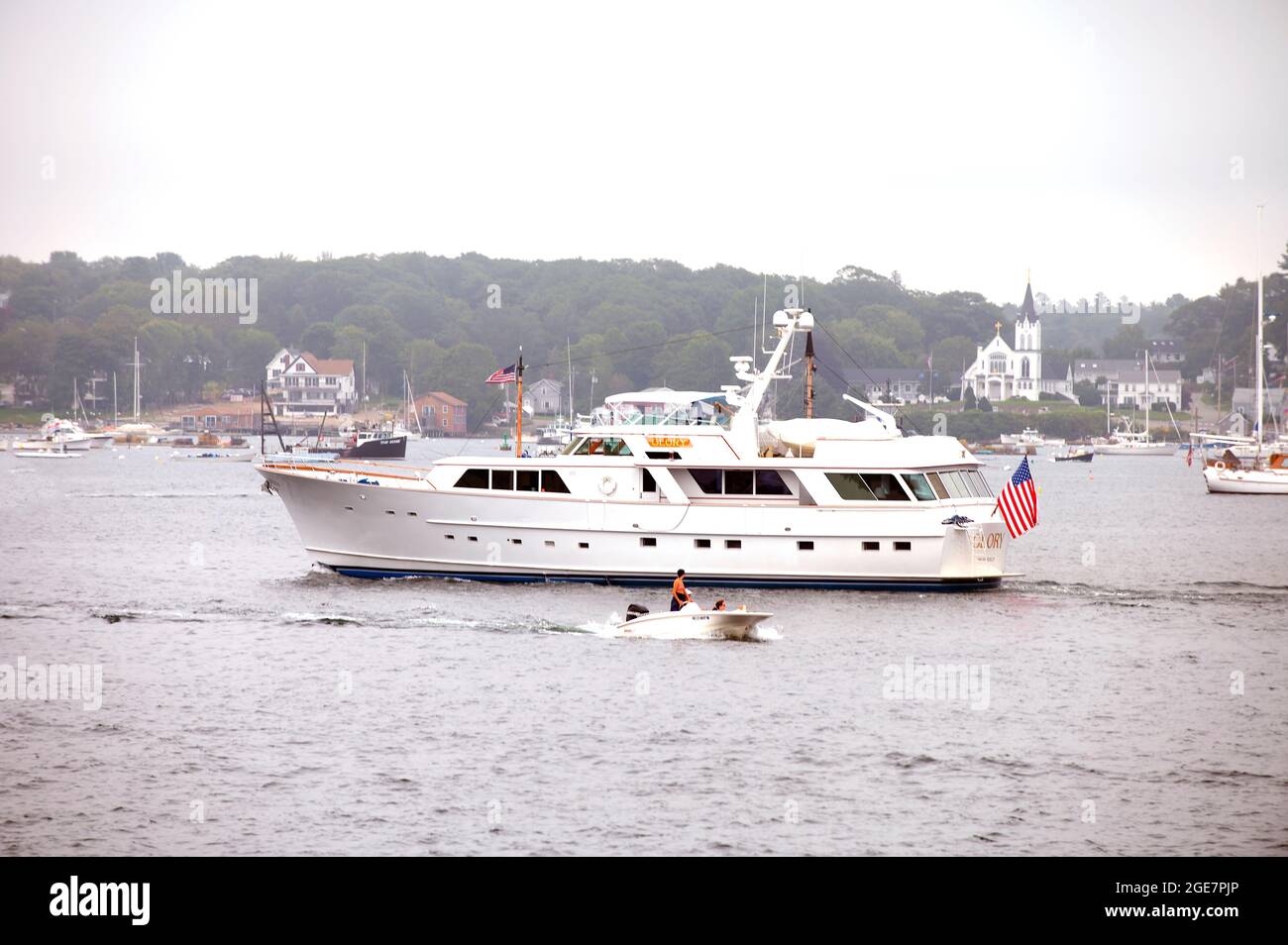 Una piccola barca passa un yacht di lusso ancorato a Boothbay Haror, Maine, USA Foto Stock