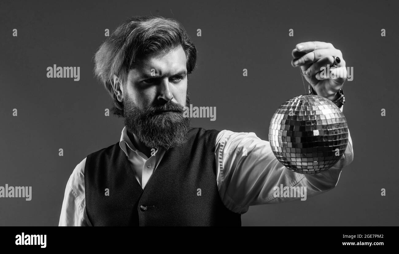 tempo per la festa. discoteca super cool. hipster brutale maturo. uomo con barba tenere specchio disco palla. concetto di festa aziendale. disco uomo in tuta Foto Stock