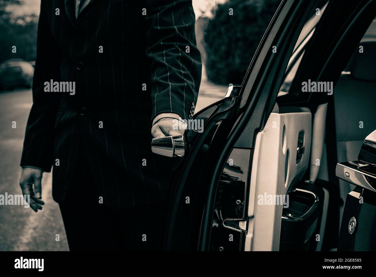 Autista che apre la porta del passeggero dell'auto di lusso Foto Stock