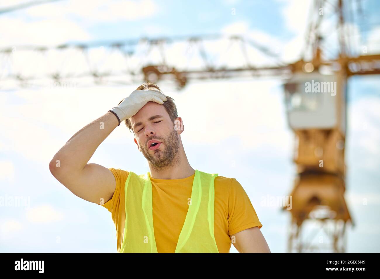 Costruttore esausto che tocca il capo con una mano guanto Foto Stock