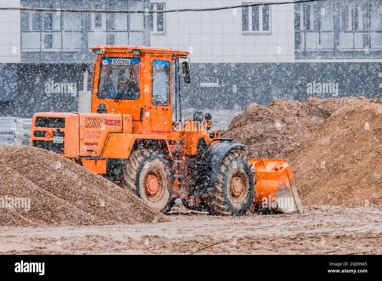 Bielorussia, Minsk - 14 marzo 2020: Trattore industriale in inverno su un cantiere si distezza la sabbia. Foto Stock