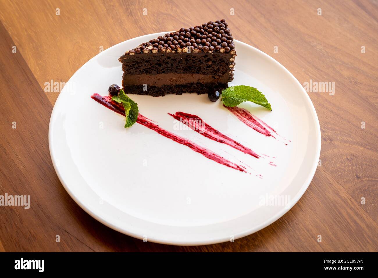 Un Primo Piano Di Una Fetta Di Torta Al Cioccolato Su Un Piatto Con Foglie Di Menta E Sciroppo Per La Decorazione Foto Stock Alamy