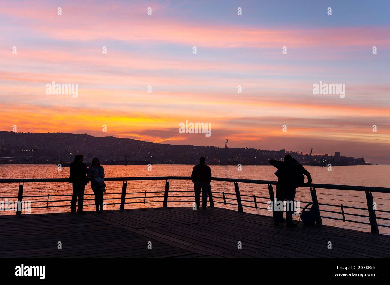 Silhouette di persone che godono il tramonto sul molo principale di Valparaiso, Cile. Foto Stock