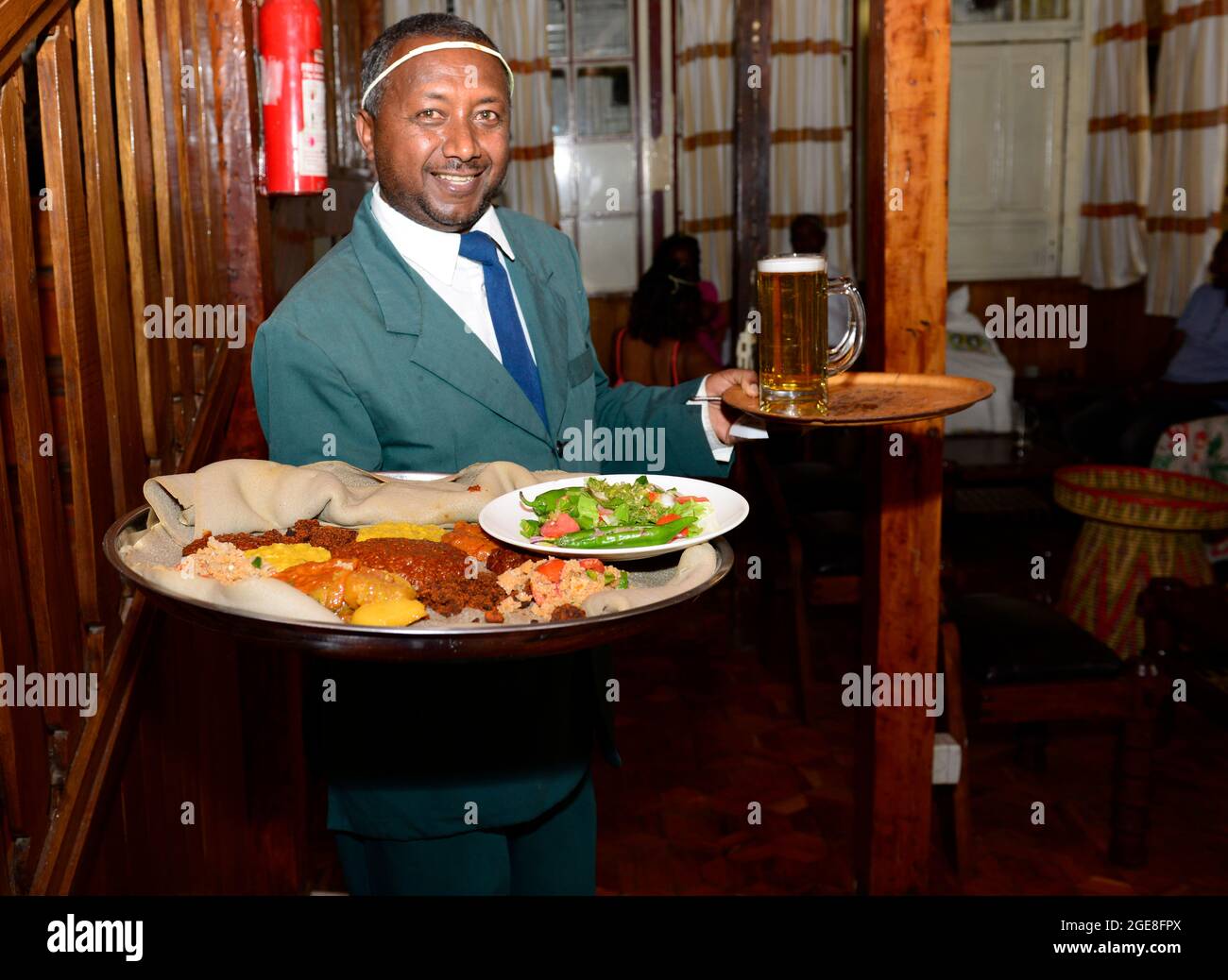 Un cameriere che serve un piatto injera al Finfine Cultural Restaurant ad Addis Abeba, Etiopia. Foto Stock