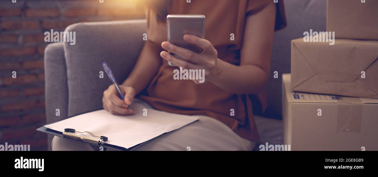 Donna che tiene il telefono e ottiene l'ordine, inizio della vendita in linea Foto Stock