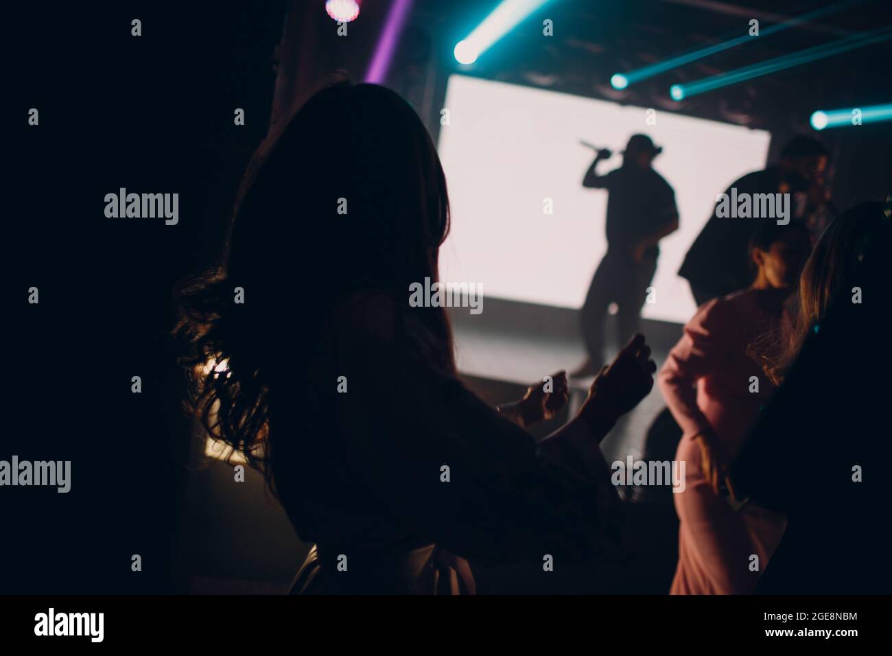 La silhouette dell'uomo del cantante al buio canta in un microfono durante un concerto. Foto Stock