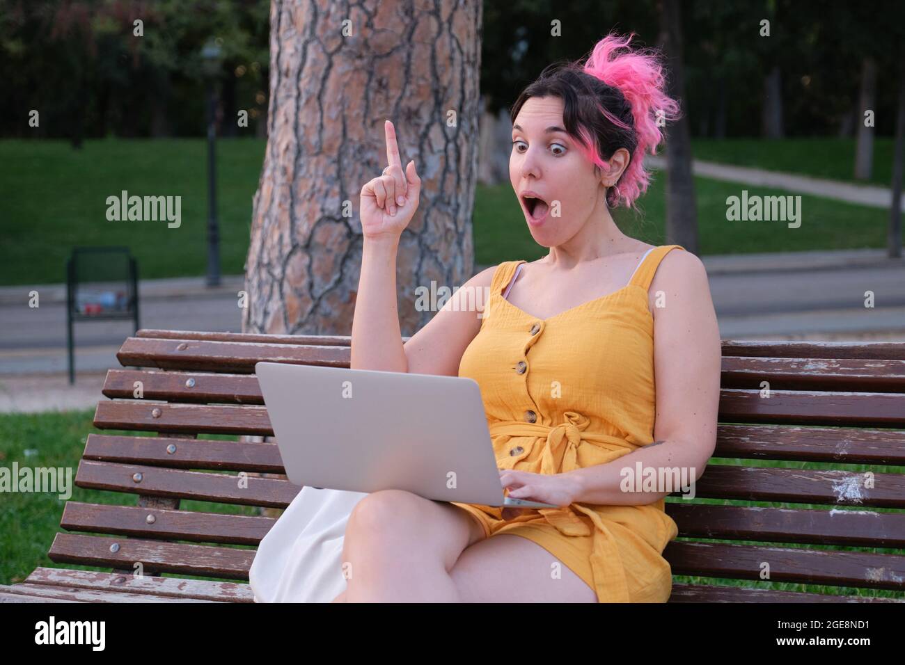 Giovane donna caucasica con capelli rosa che ha una grande idea di fronte a un computer portatile. Foto Stock