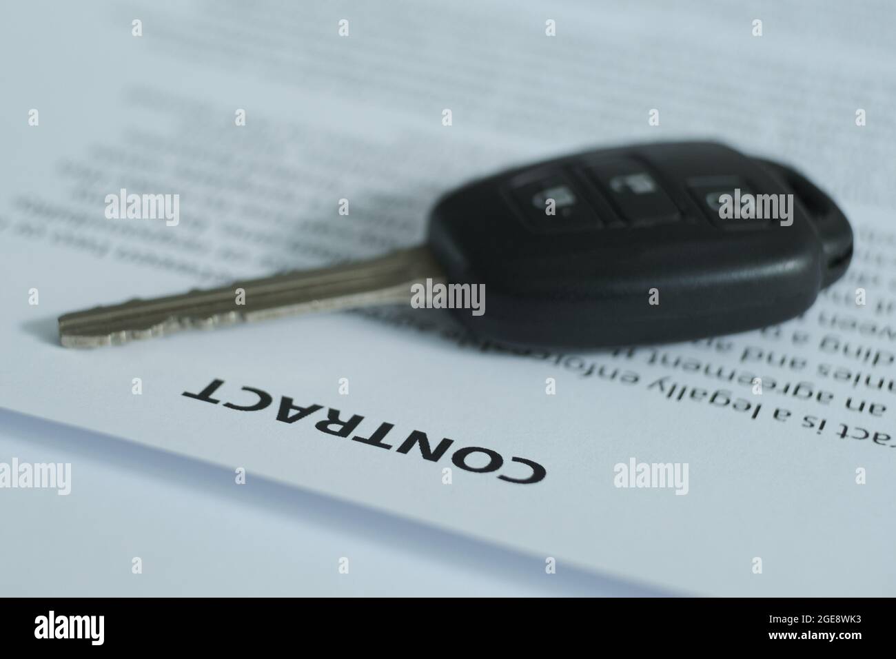 C'è un contratto e le chiavi di automobile sul tavolo, l'enfasi è sul nome del documento e le chiavi. Immagine sfocata. Foto Stock