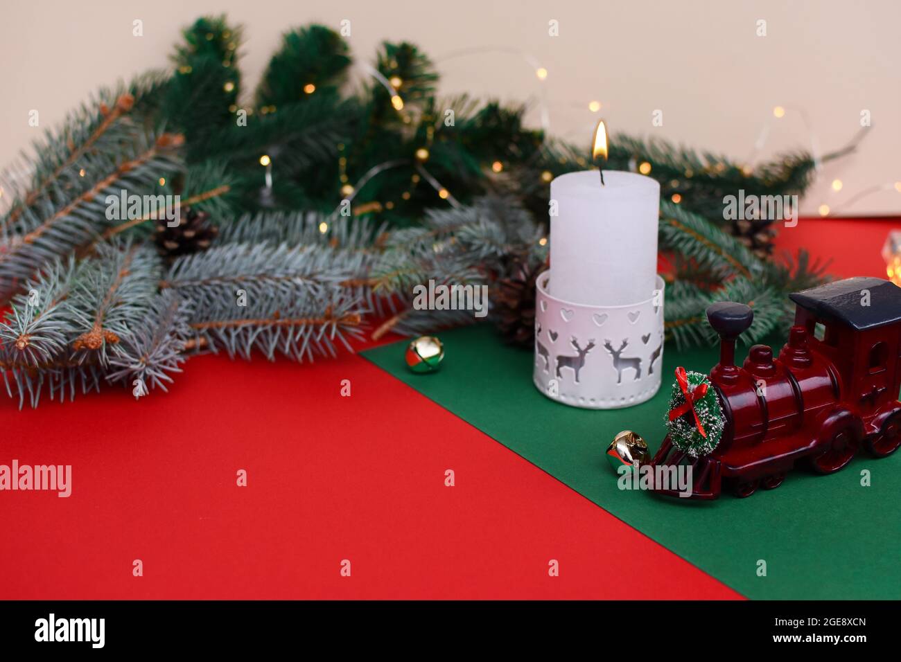 Una carta di Natale. Una candela che brucia, rami di abete, un treno di Capodanno. Foto Stock