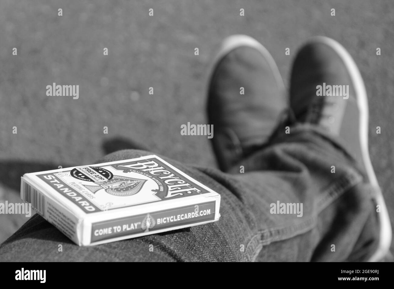 Scatto in scala di grigi di una scatola di un mazzo di carte sulla gamba di una persona Foto Stock