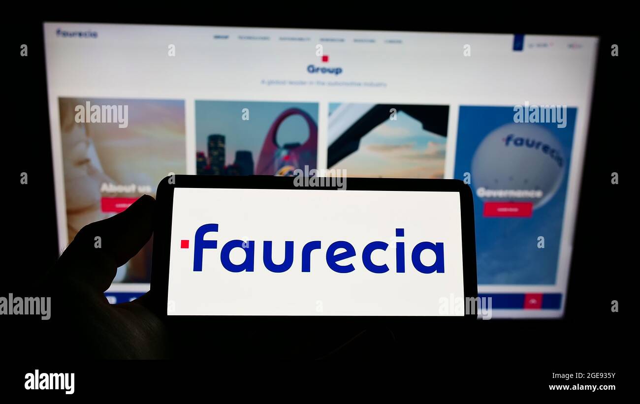 Persona che detiene smartphone con il logo del fornitore automobilistico francese Faurecia se sullo schermo di fronte al sito web. Mettere a fuoco il display del telefono. Foto Stock