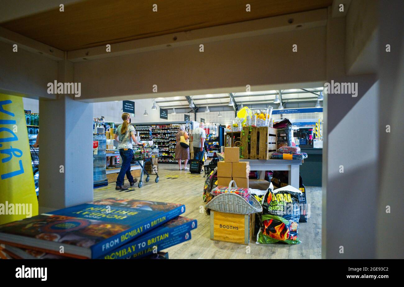 Guardando attraverso le librerie nel supermercato principale presso gli stand di Burscough, Lancashire, durante l'uso della maschera covid Foto Stock