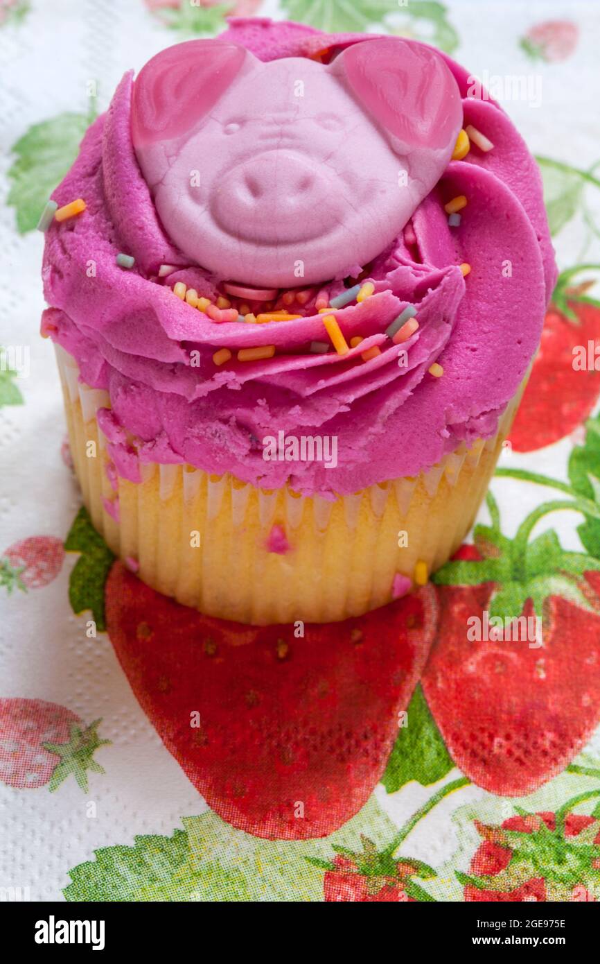 Torta Percy Pig party con cupcake di M&S, sita su tovagliolo con serviette di fragole d'estate Foto Stock
