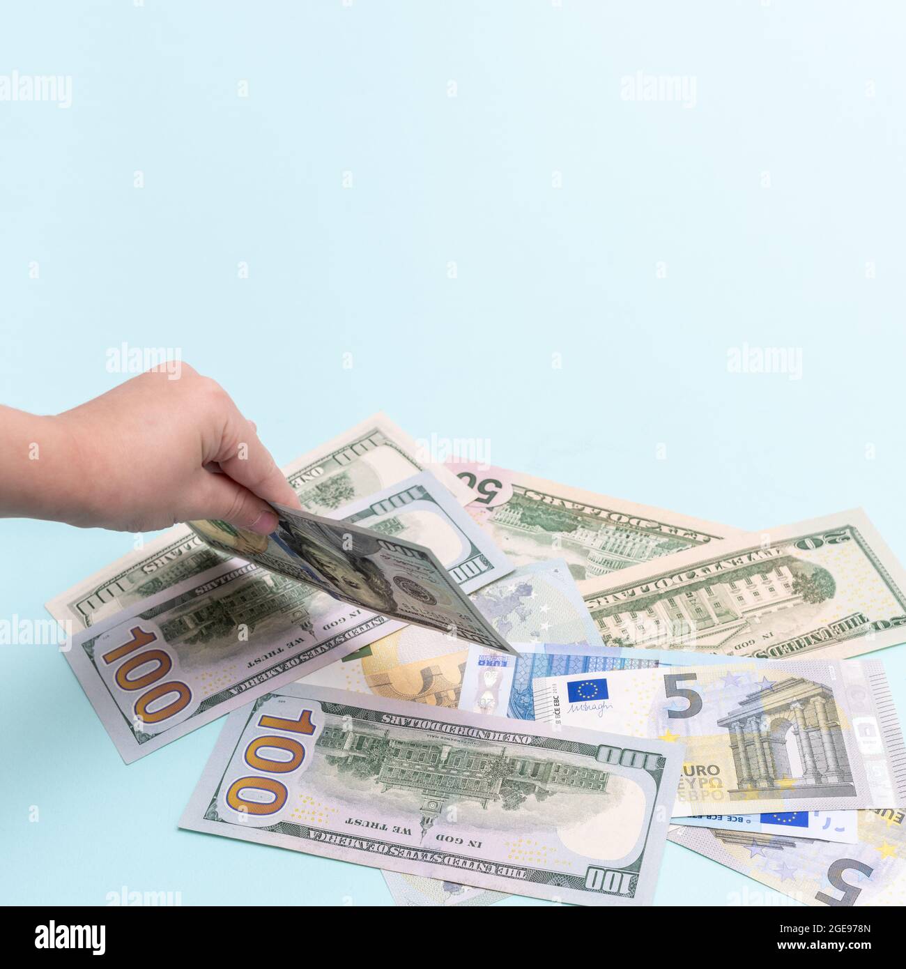 Mano del bambino che tiene una fattura di cento dollari, cornice quadrata, spazio di copia. Costo di allevare un bambino. Corsi business per bambini. Insegnare ai bambini a m. Foto Stock
