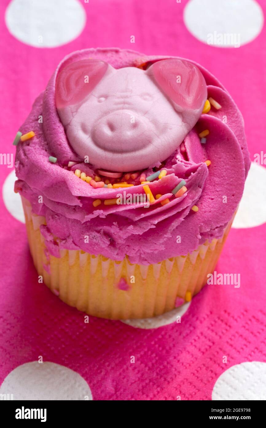 Torta Percy Pig party con cupcake di M&S, sita su tovaglietta con polka a pois rosa Foto Stock