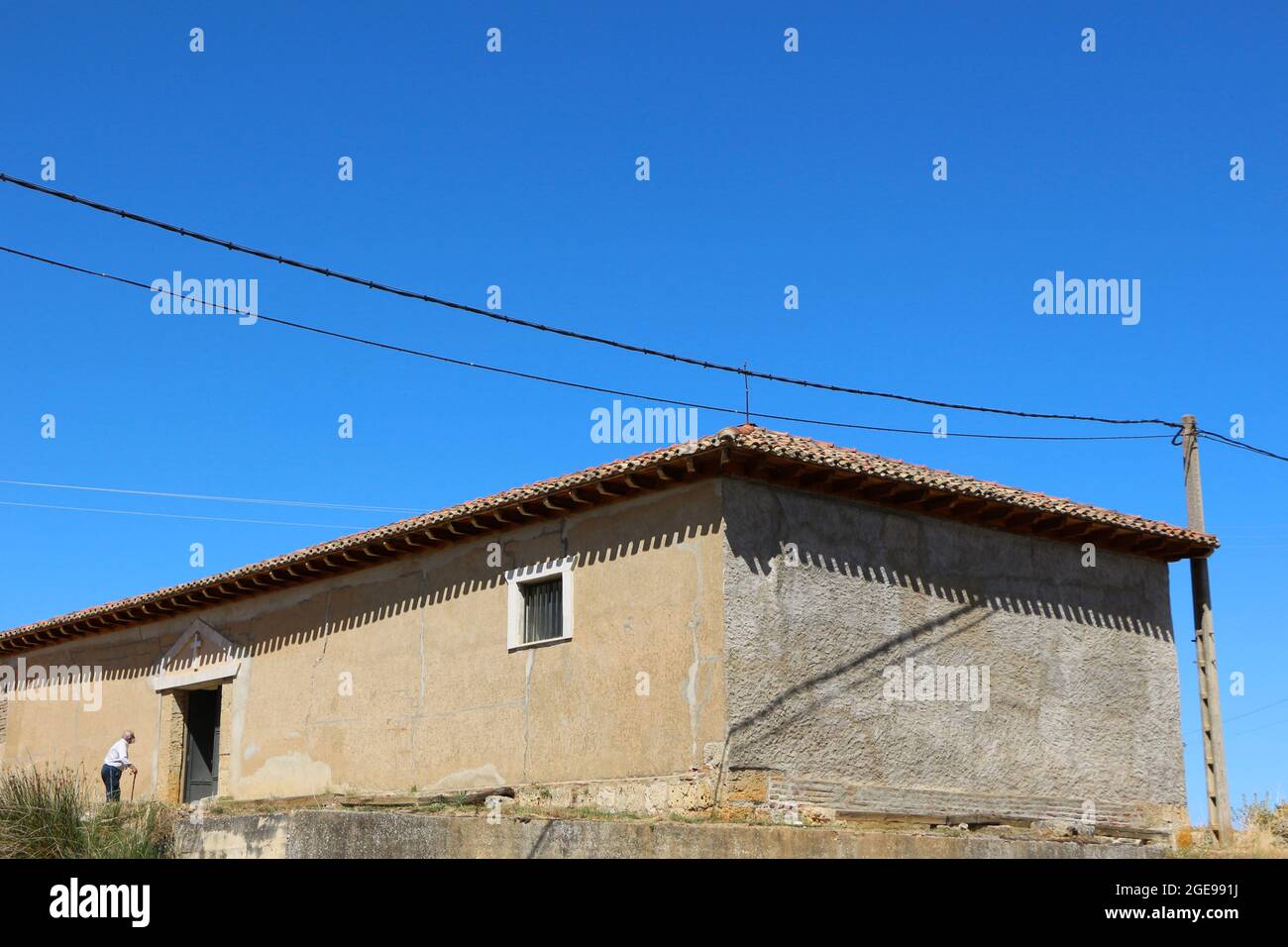 Uomo anziano con un bastone che entra nella Cappella Ermita de San Roque Lantadilla Cantabria Spagna il giorno della messa di celebrazione 16 agosto 2021 Foto Stock