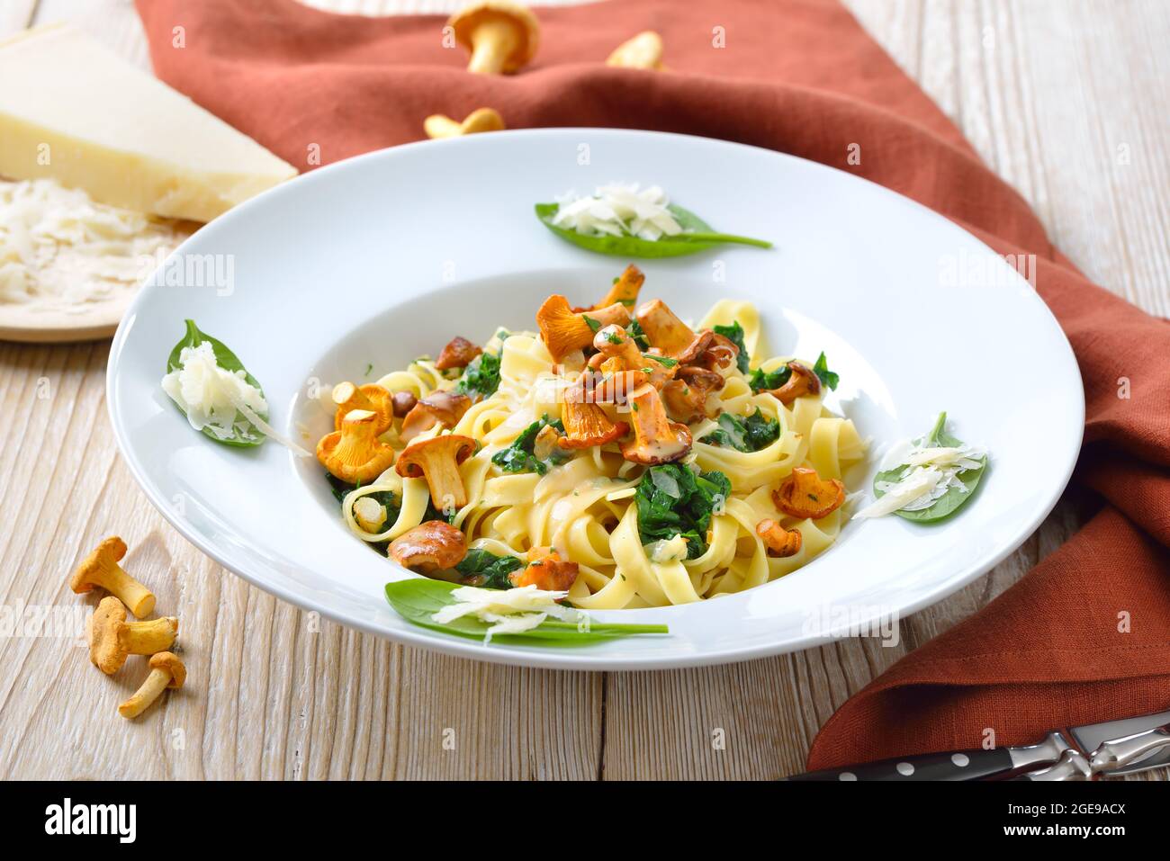 Deliziosa pasta italiana con chanterelle fresche, spinaci giovani, salsa alla crema e parmigiano Foto Stock