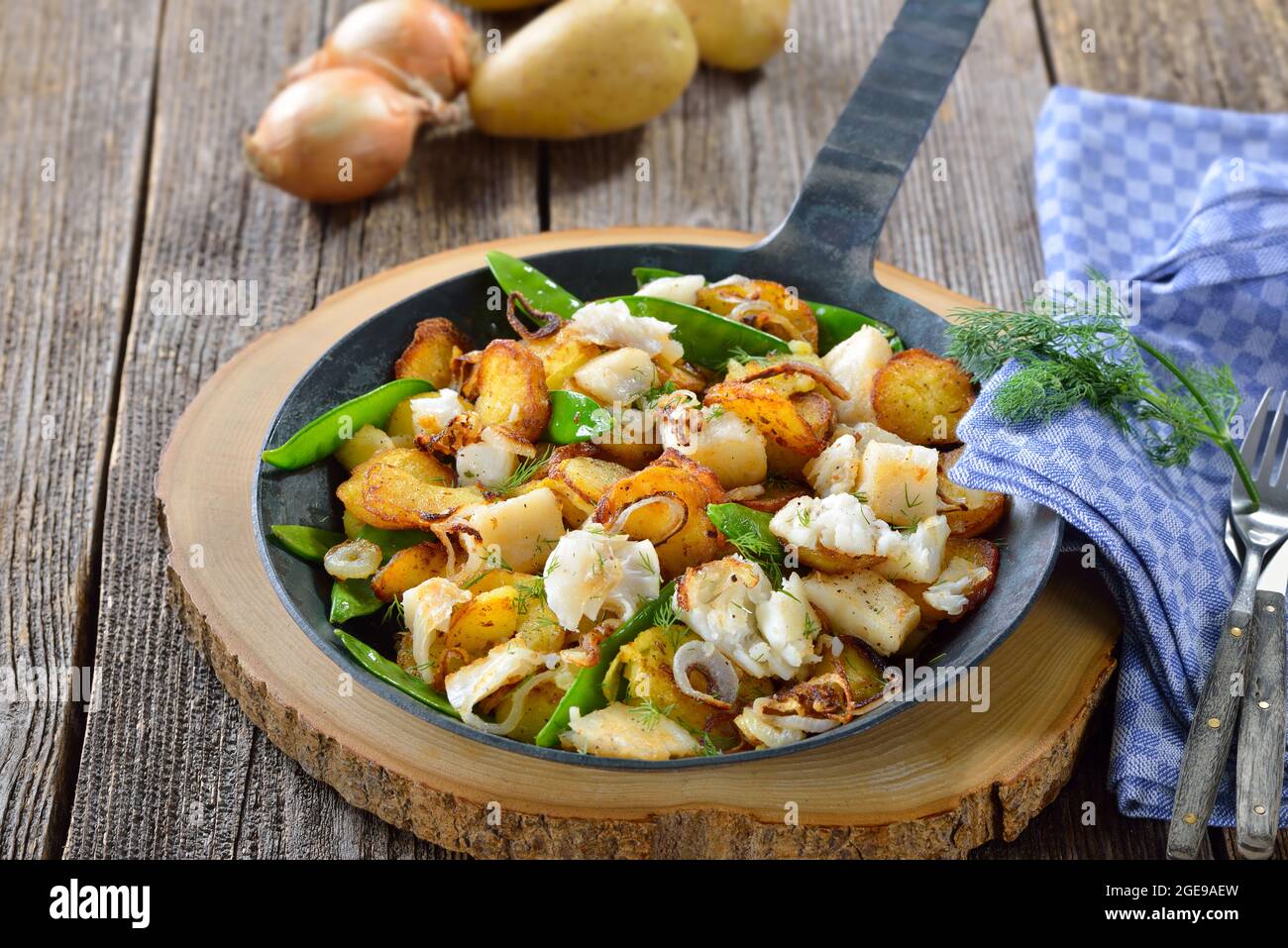 Patate fritte con pezzi di filetto di ippoglosso, piselli di zucchero e anelli di cipolla, spesso servite in padella Foto Stock