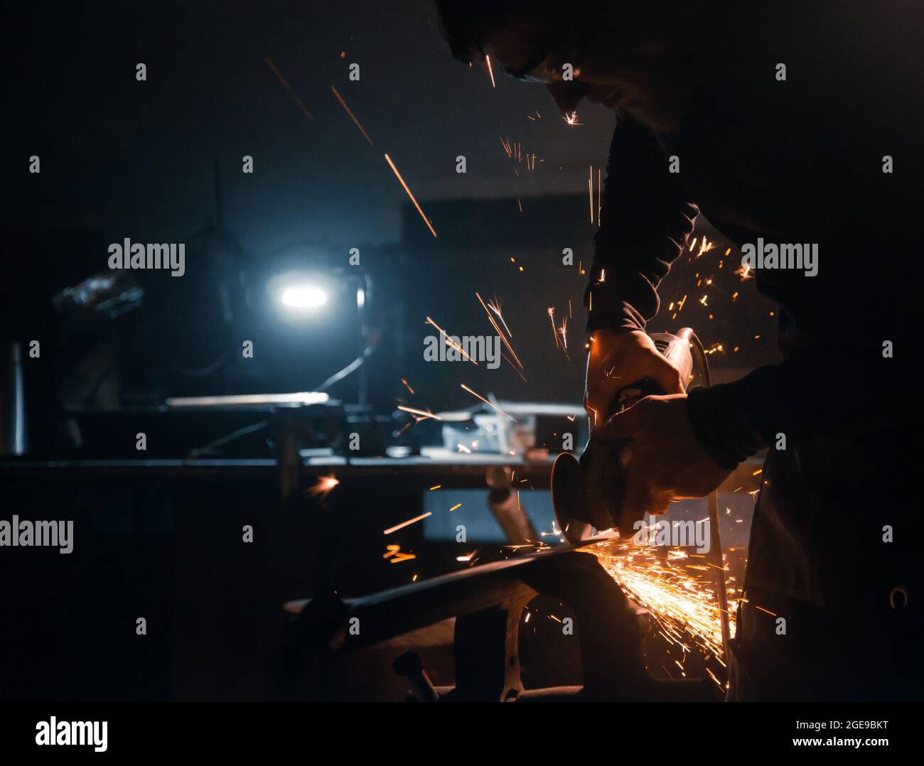 L'operatore taglia il metallo con una sega circolare, le scintille volano ai lati. Foto Stock