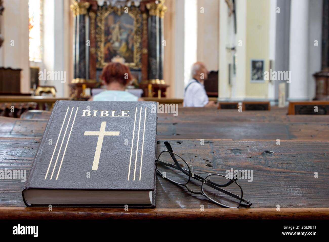 La Bibbia sulla tavola di una panchina di preghiera nella chiesa con un altare. Foto Stock