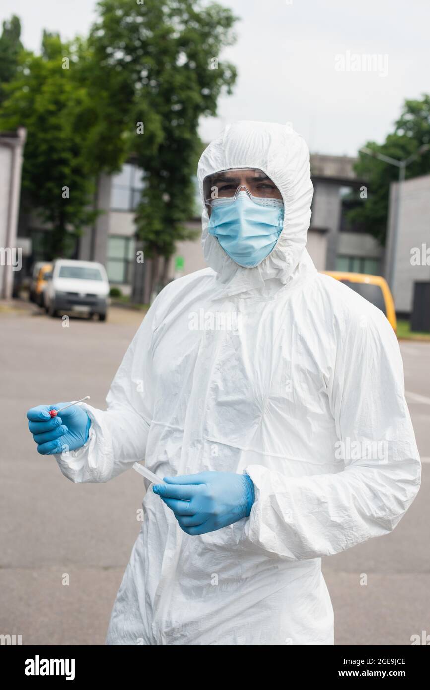 Lavoratore medico in tuta di Hazmat che tiene test pcr all'aperto Foto Stock