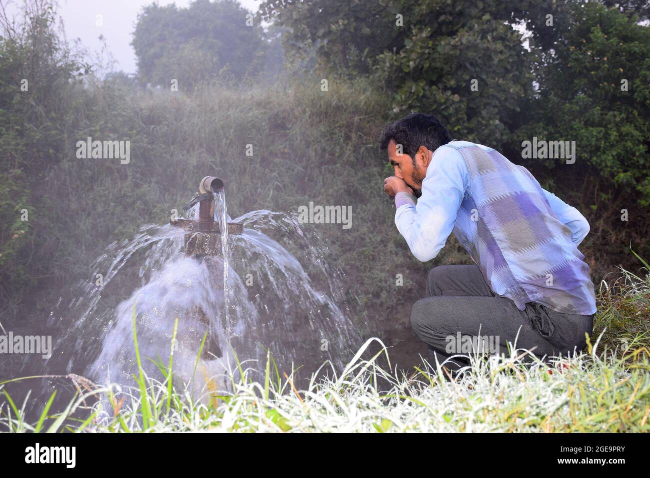 Attrezzature agricole per l'irrigazione di campo, un agricoltore indiano acqua potabile da getto d'acqua traboccante sulla sua fattoria, pioggia nebbia, fuoco selettivo Foto Stock