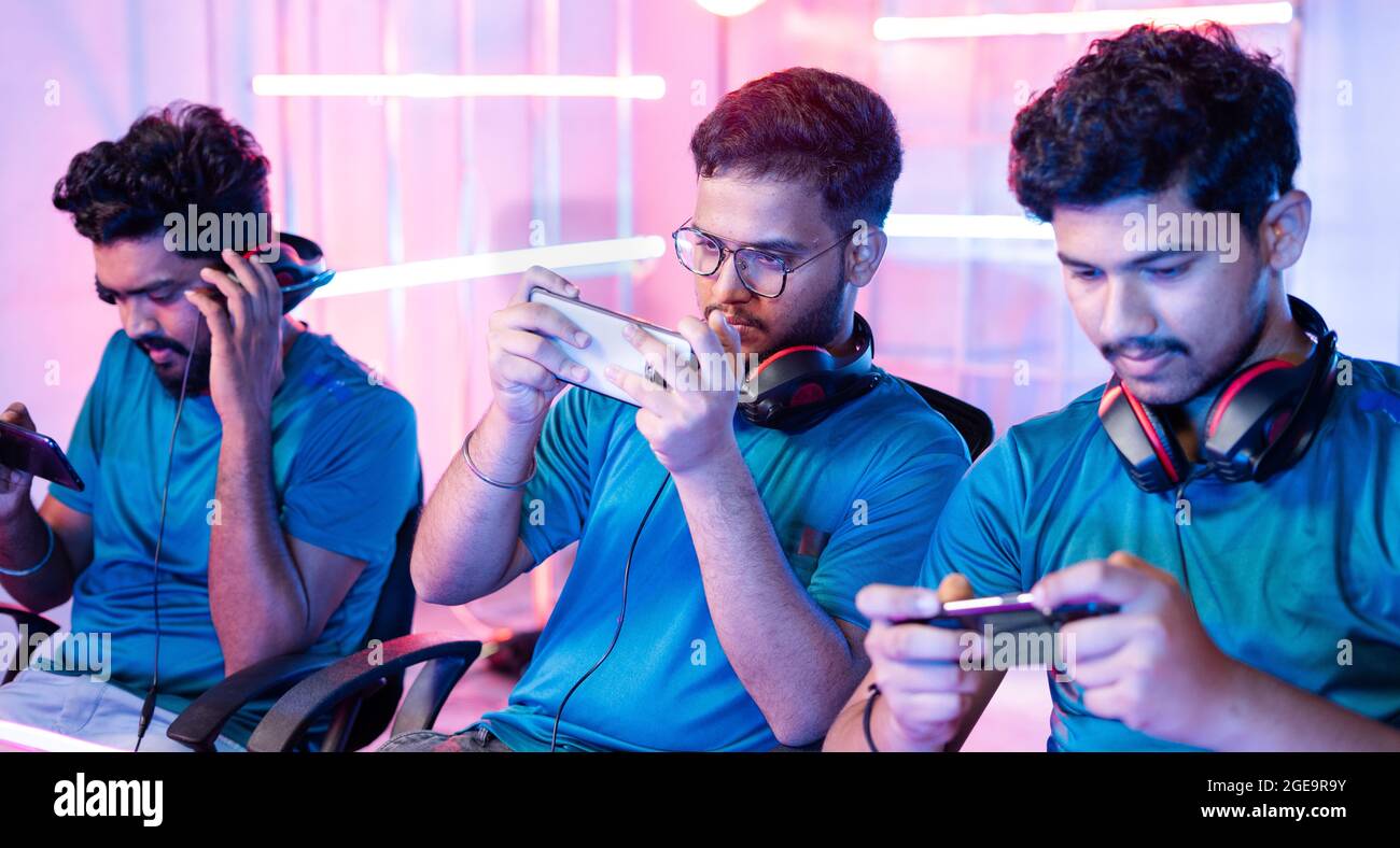 Team di giovani giocatori professionisti che giocano a videogame dal vivo sul telefono cellulare parlando con le cuffie alla lega di eSport. Foto Stock
