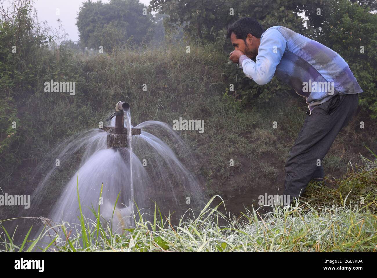 Attrezzature agricole per l'irrigazione di campo, un agricoltore indiano acqua potabile da getto d'acqua traboccante sulla sua fattoria, pioggia nebbia, fuoco selettivo Foto Stock