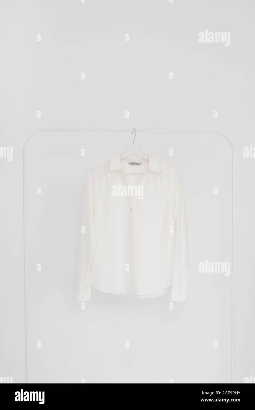 Blusa bianca con maniche lunghe su appendiabiti. Foto Stock