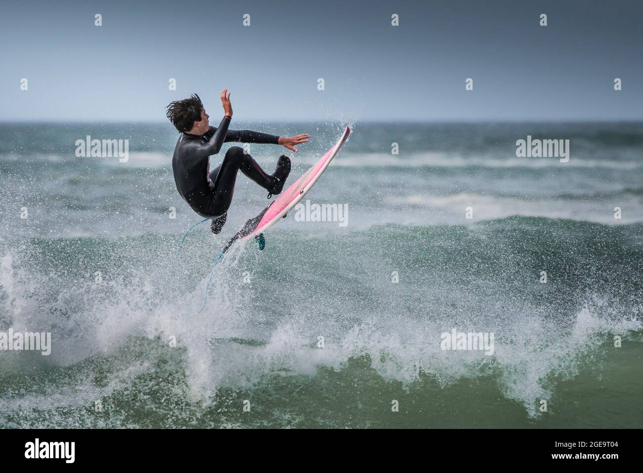 Un surfista che esegue un trick aereo in mare a Fistral a Newquay in Cornovaglia. Foto Stock