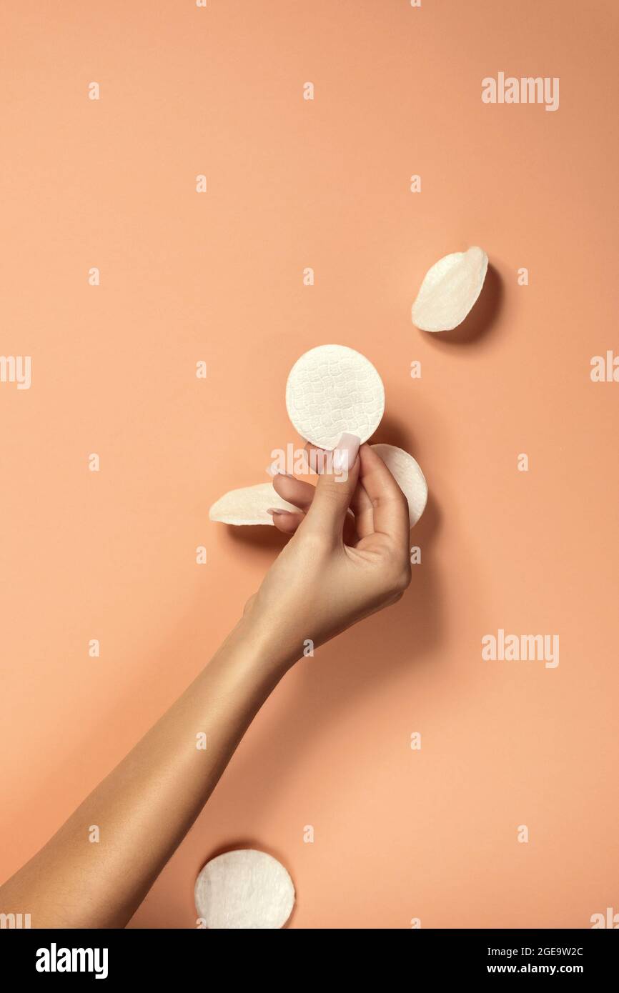 Crop Unriconoscibile Donna con manicure e delicata pelle che dimostra pulito cotone tampone su sfondo beige Foto Stock