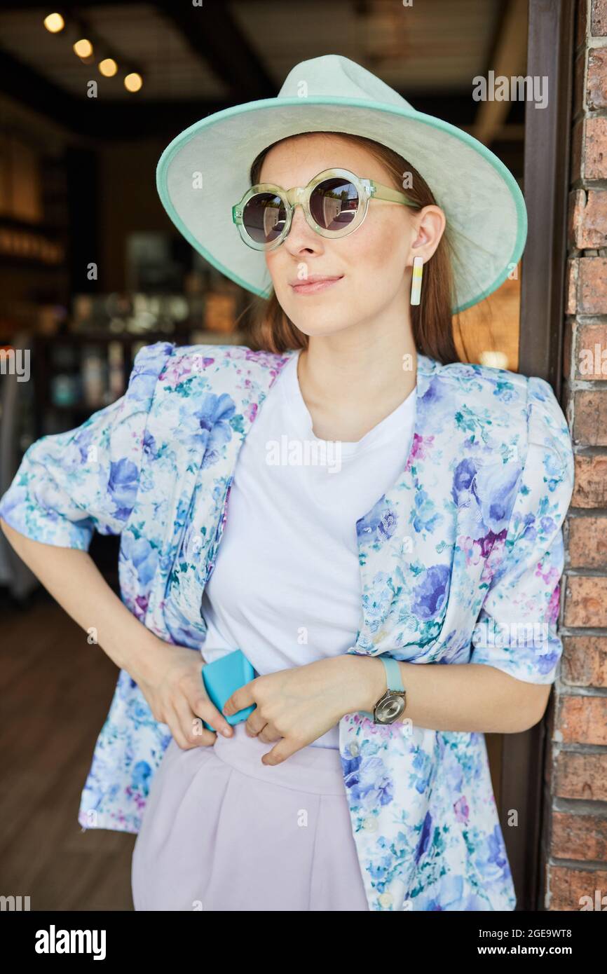 Calmo ispanico femmina in abbigliamento sportivo chiusura occhi e gesturing Gyan mudra mentre seduto in posa di Lotus su tappeto vicino divano durante yoga sessione in vita Foto Stock