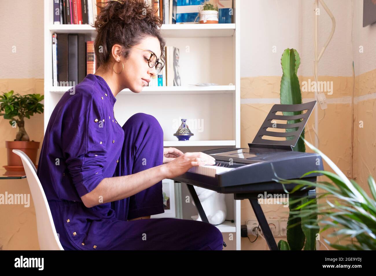 Giocoso pazzo bearded maschile ciclista saltando con bocca aperta mentre giocare ukulele strumento vicino bici su strada vicino sfondo rosso Foto Stock