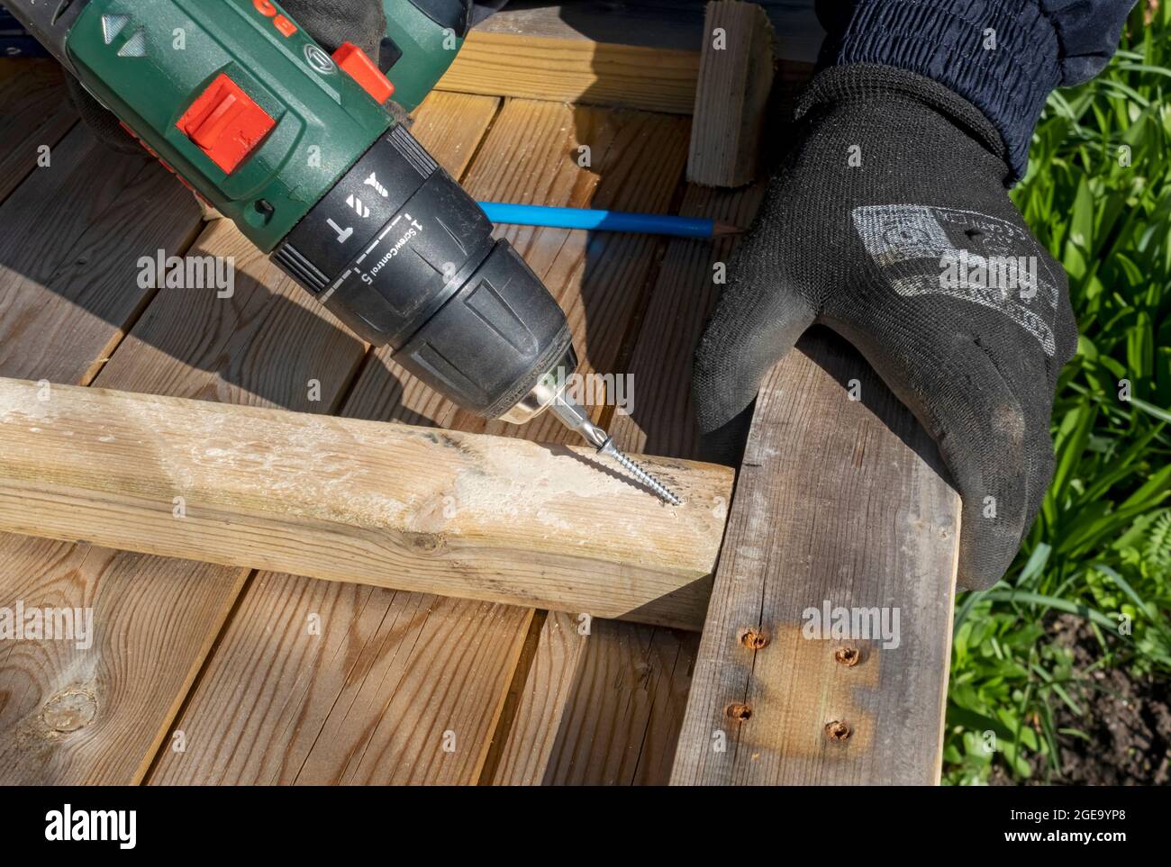 Primo piano dell'uomo con un cacciavite a batteria per fissare la vite nel legno. Foto Stock