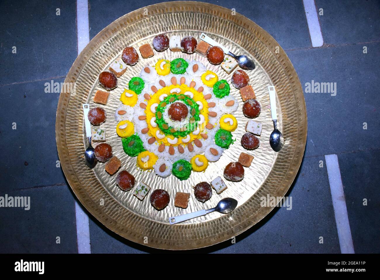Bella torta fatta di riso colorato, decorato con frutta secca e dolci in piatto di ottone Foto Stock