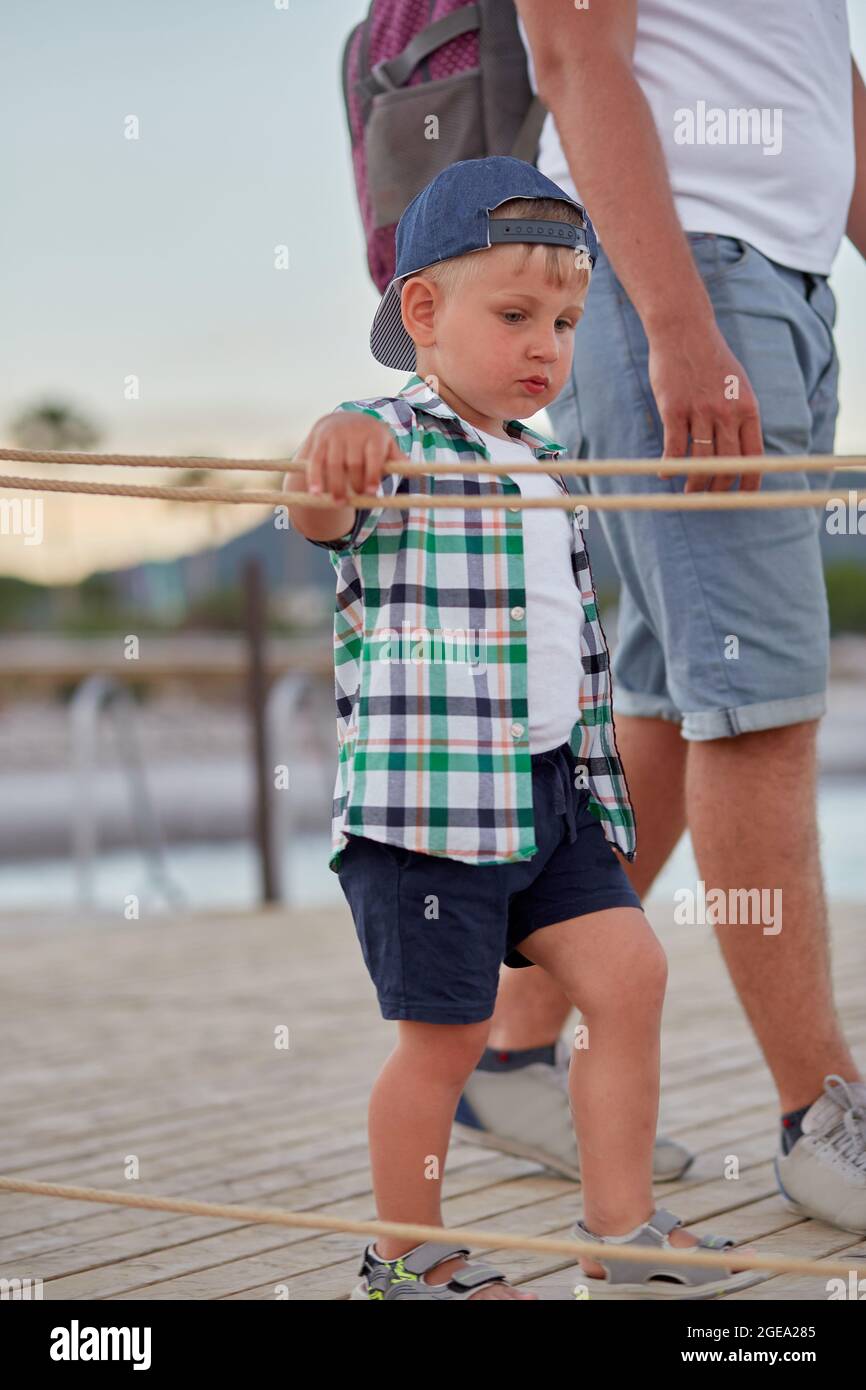Padre e figlio camminano insieme vicino al mare. Vacanze estive. Fotografia dell'ora blu. Tempo di famiglia. Foto di alta qualità Foto Stock