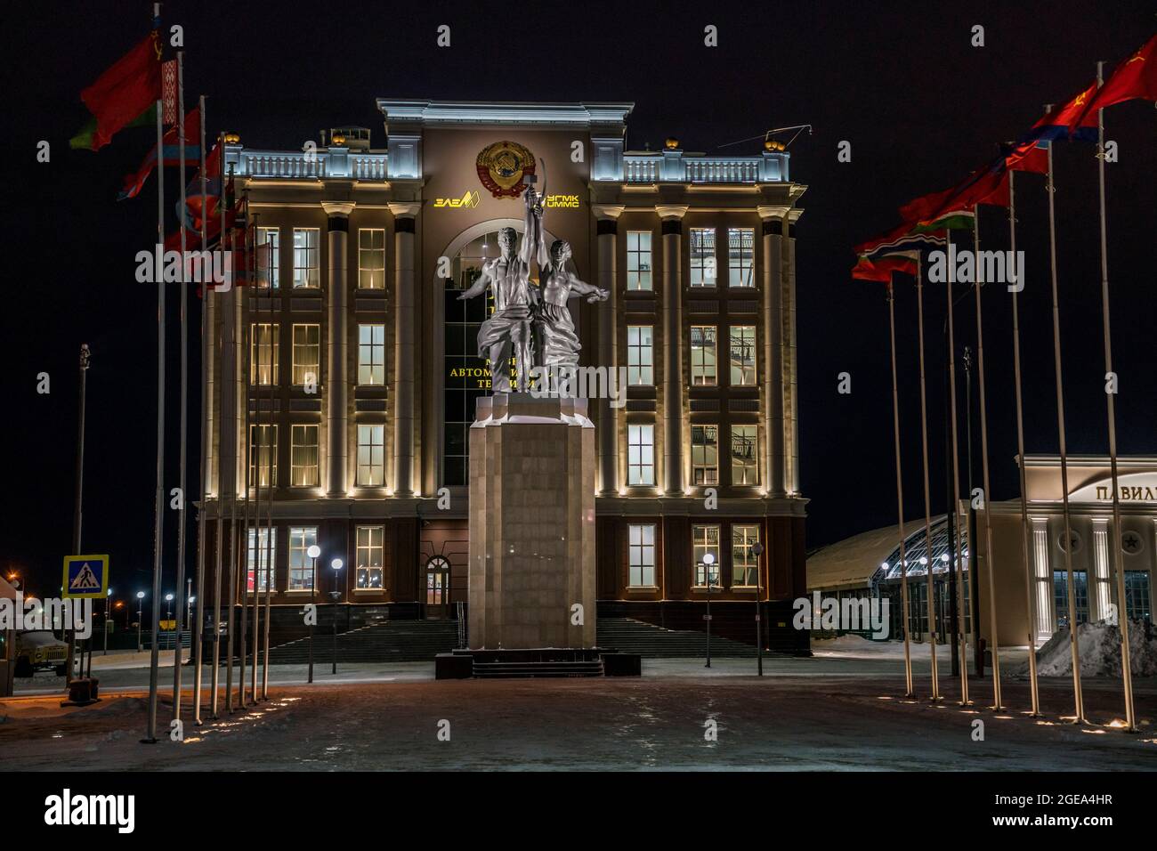 Una famosa statua di operai di epoca sovietica che sollevano il martello e la falce è fiancheggiata da file di bandiere in un museo dei veterani a Ekaterinburg, in Russia. Foto Stock