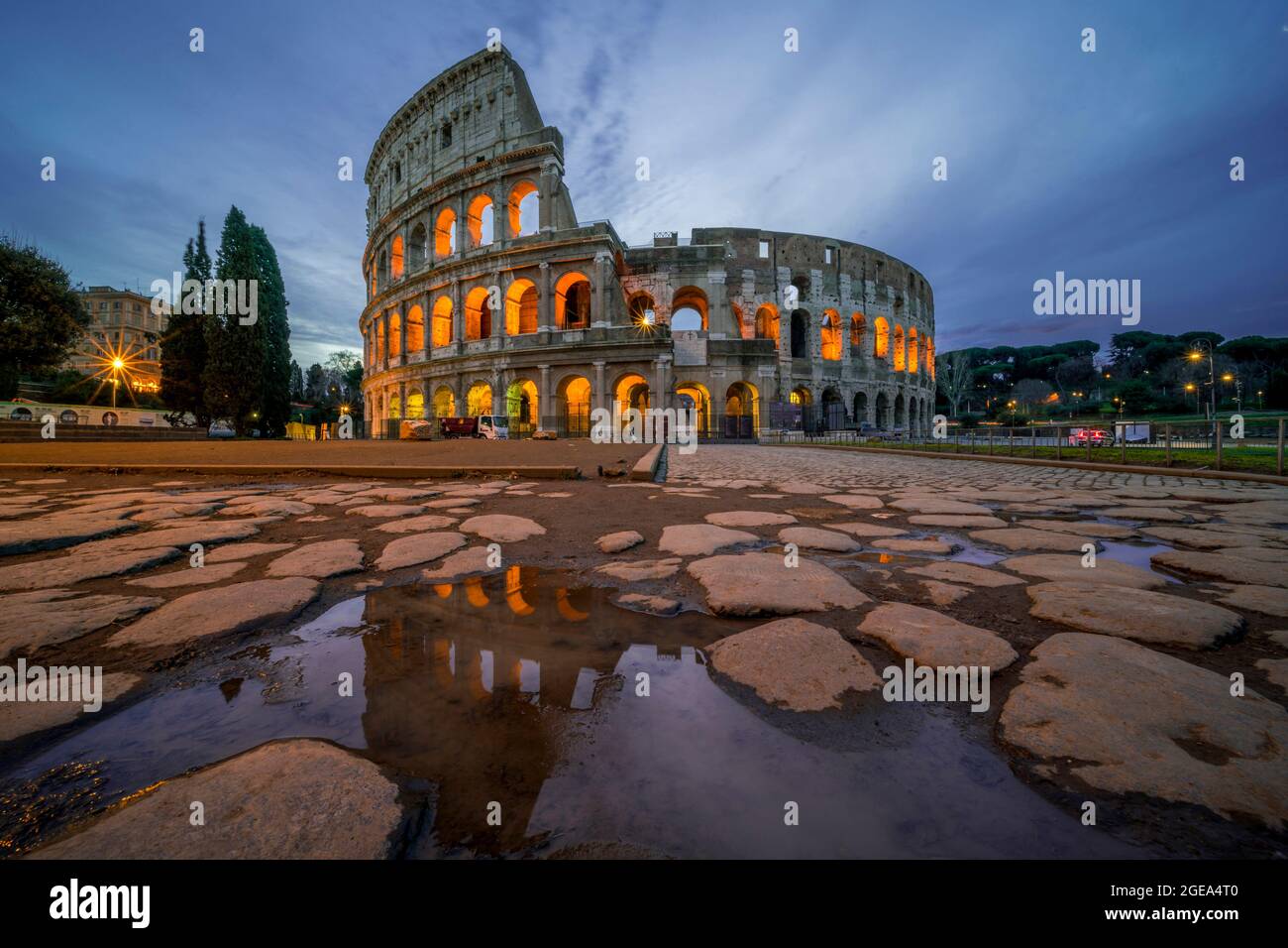 Il famoso Colosseo di Roma riflette la sua forma iconica nelle piscine raccolte in antichi sentieri acciottolati. Foto Stock