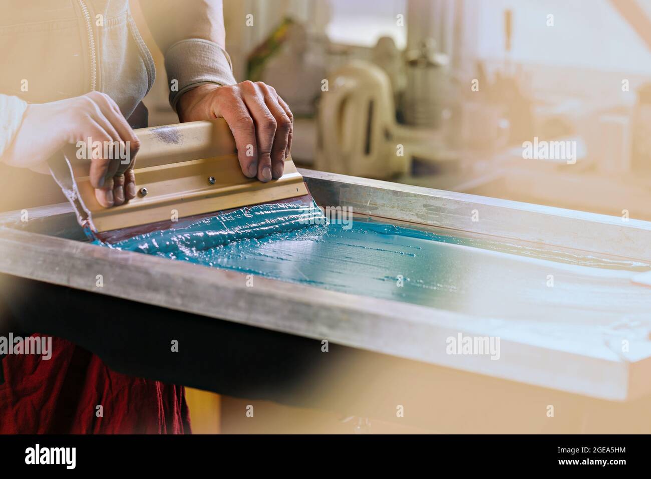 produzione serigrafia. serigrafia tessile serigrafia printery. stampa serigrafica manuale studio di progettazione. foto mani maschili con spatola Foto Stock