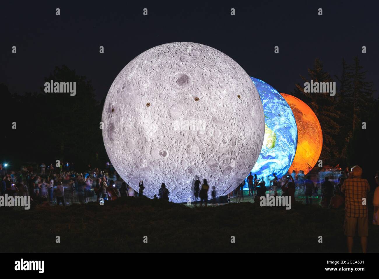 BRNO, Repubblica Ceca - Agosto, 14. 2020 modello gonfiabile gigante dei pianeti Marte, Terra e Luna di notte con sagome di persone. Sistema solare Foto Stock