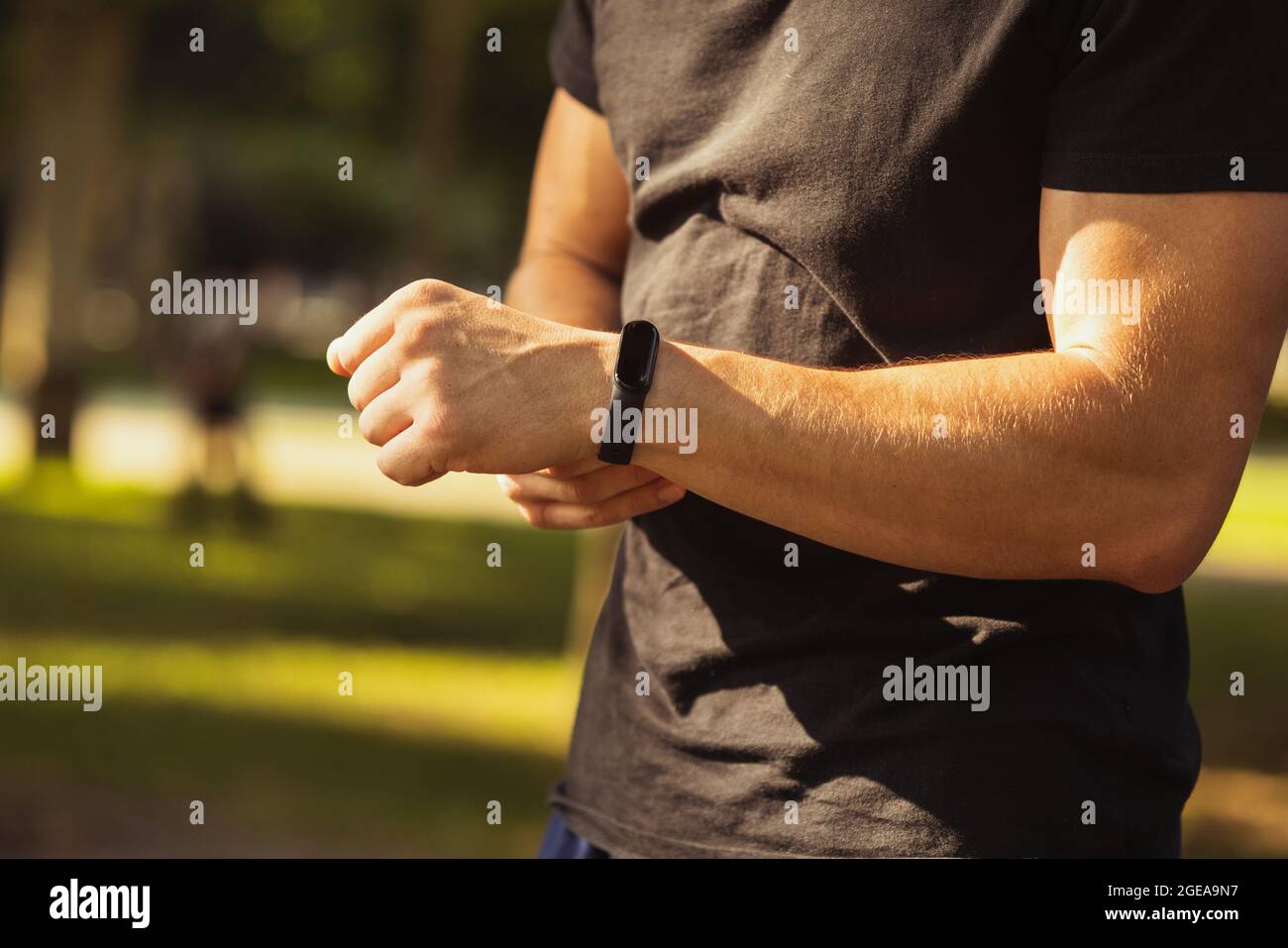 Giovane uomo caucasico, atleta che misura il polso, battito cardiaco con  bracciale fitness dopo l'allenamento su campo sportivo. Primo piano Foto  stock - Alamy