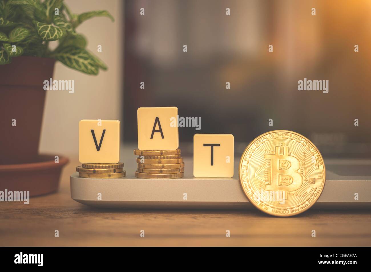 IVA con bitcoin criptovaluta concetto di business background. Tasse moderne con moneta criptata. Scrivania con computer portatile, parola IVA e moneta d'oro Foto Stock