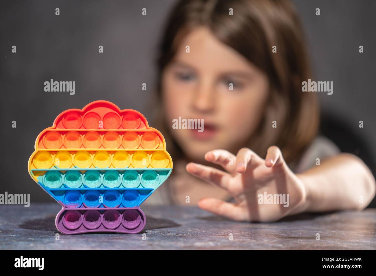 Bambina che gioca con arcobaleno colorato pop it silicone giocattolo antistress Foto Stock