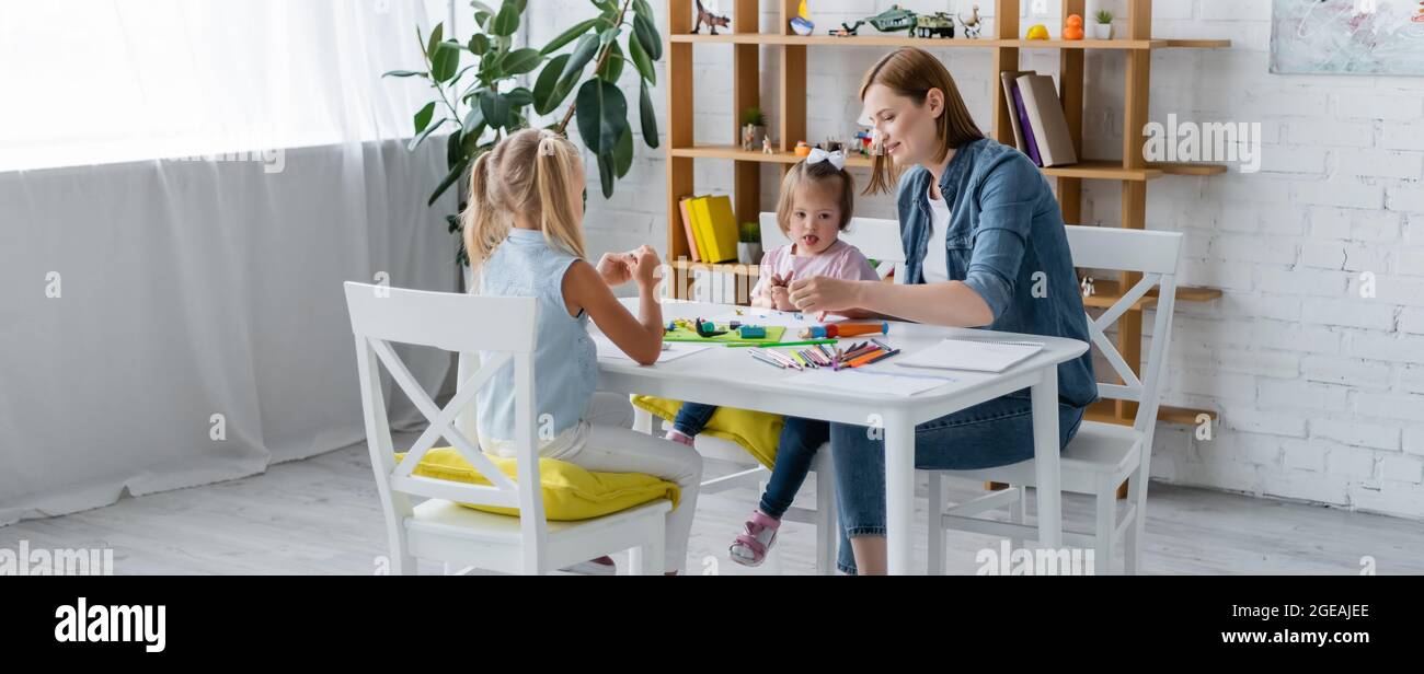 scuola materna insegnante di plastilina di stampaggio con bambino disabili e ragazza preschooler, striscione Foto Stock