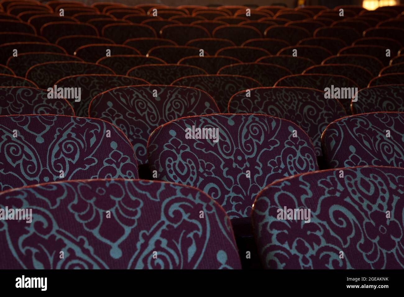 Sedili di colore Bordeaux con un motivo decorato in luce soffusa in un vecchio teatro Foto Stock